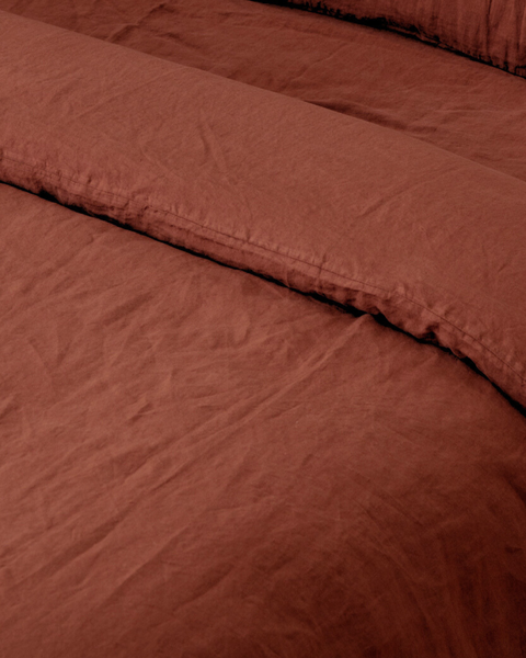 Lniane stonewashed prześcieradło z gumką i poszwa Terracotta w odcieniu terakoty, na zasłanym łóżku
