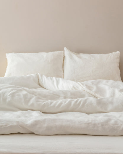 Cream stonewashed flax linen pillowcases and duvet on a styled bed against a neutral wall