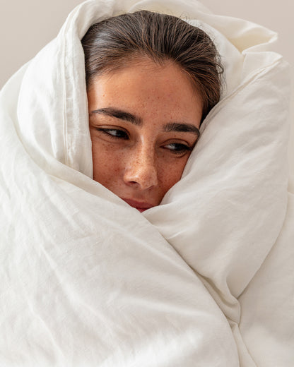 Woman wrapped in Cream stonewashed flax linen, with her face peeking out